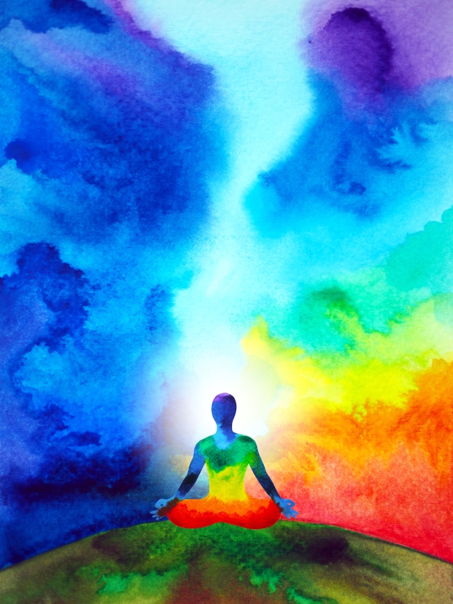 Person sitting on hill surrounded by colourful sky